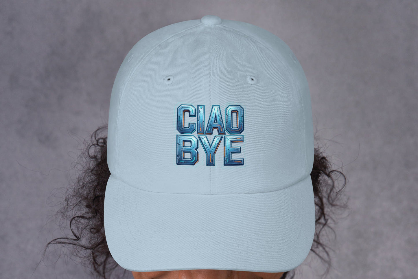 Light blue cap with 'CIAO BYE' text worn by a person against a gray background