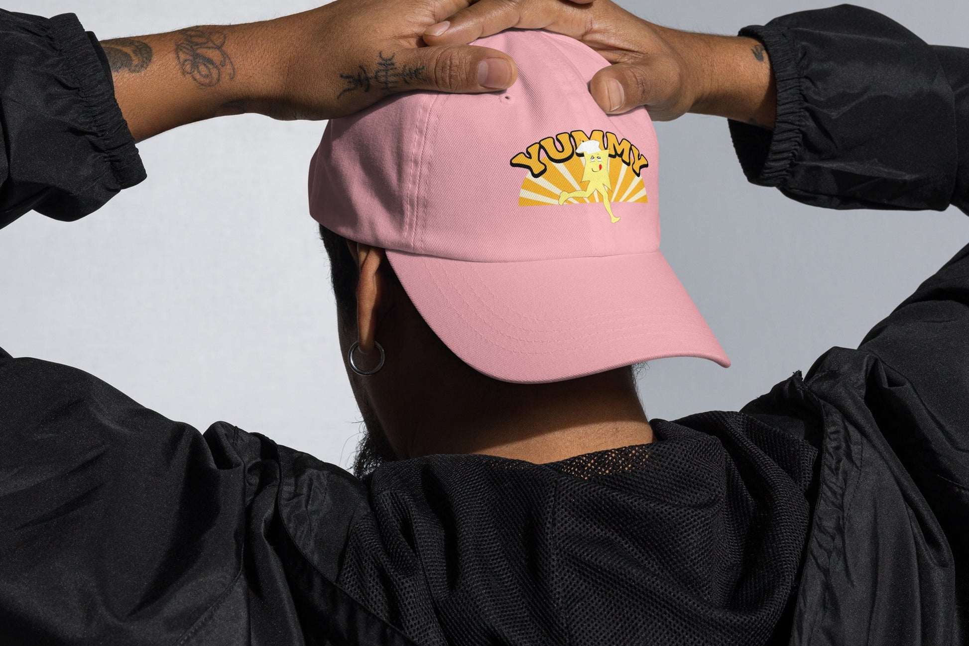 Person wearing a pink cap with YUMMY  text, and YUMMY character in yellow and white