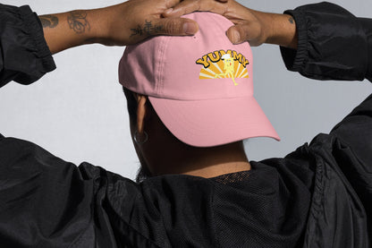 Person wearing a pink cap with YUMMY  text, and YUMMY character in yellow and white