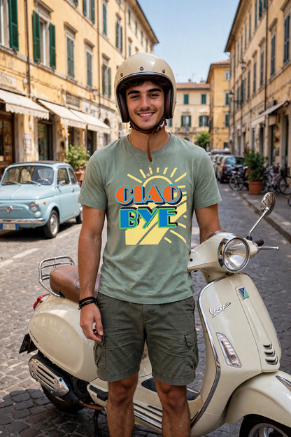A man wearing a beige helmet and a green graphic t-shirt with Ciao Bye text stands next to a cream-colored Vespa scooter on a cobblestone street lined with yellow buildings.