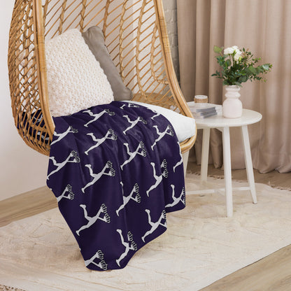 Purple blanket with white patterns draped over a wicker chair in a cozy room.The Lux character is in the white edition