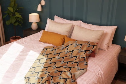 Bed with a patterned  brown blanket with Lux Runner on it and pillows in a bedroom setting