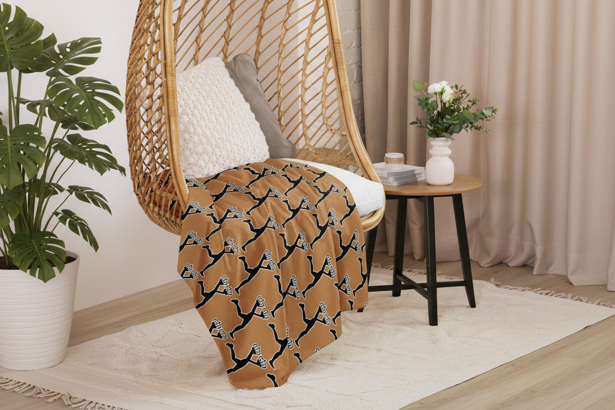 Brown blanket with black and white pattern draped over a wicker chair in a cozy room.