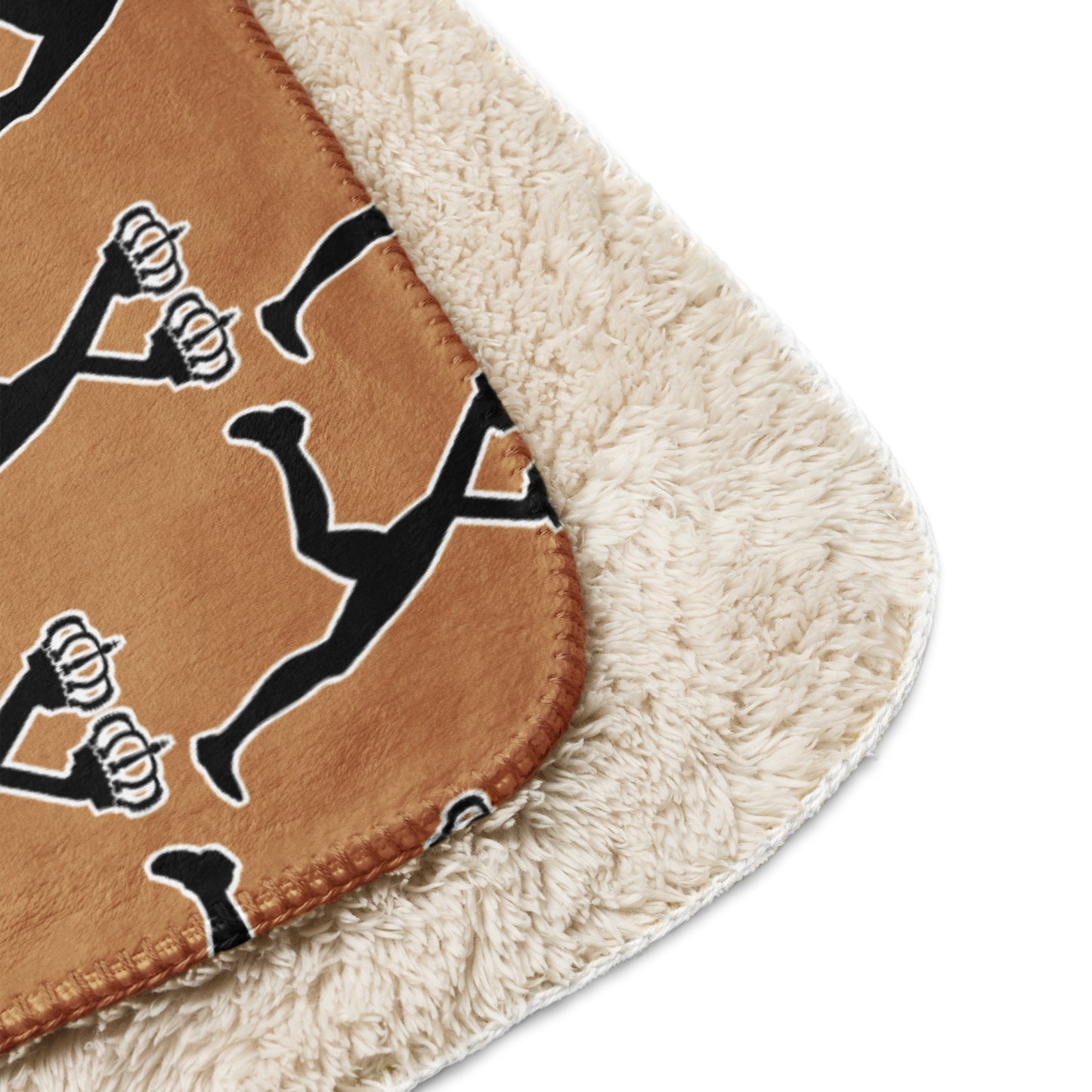 Close-up of a brown throw  sherpa blanket with black and white designs of Lux with the iconic two crowns on a beige border.