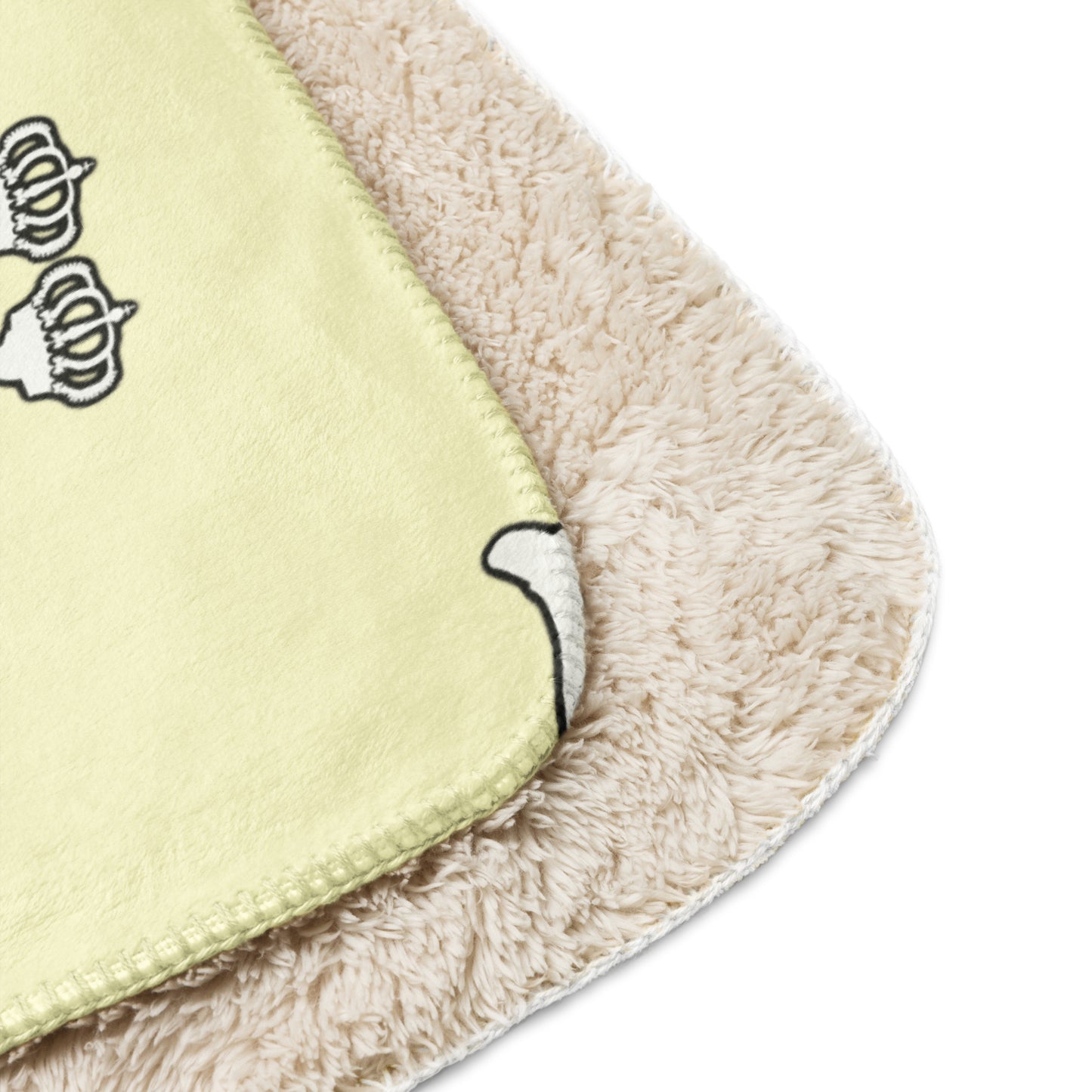 Close-up of a blanket cream color  with cartoon character Lux with crowns on it.