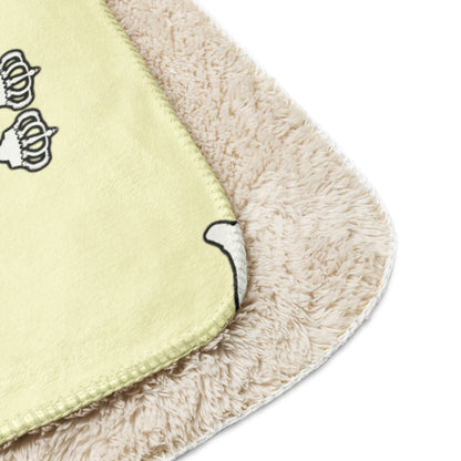 Close-up of a blanket cream color  with cartoon character Lux with crowns on it.